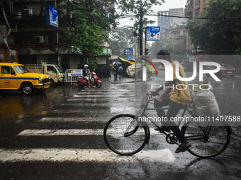 A person is riding his cycle during the heavy rain in Kolkata, India, on July 14, 2024. (