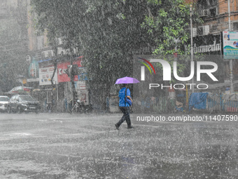 A person is crossing a street during the heavy rain in Kolkata, India, on July 14, 2024. (