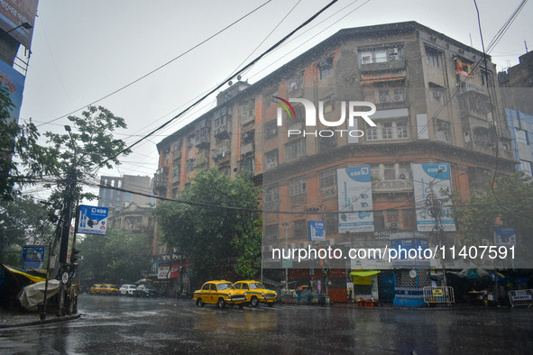 Yellow taxis are waiting at a traffic signal during the heavy rain in Kolkata, India, on July 14, 2024. 