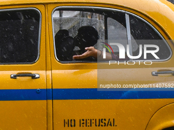 A woman is feeling the rain from a taxi during the heavy rain in Kolkata, India, on July 14, 2024. (