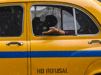 A woman is feeling the rain from a taxi during the heavy rain in Kolkata, India, on July 14, 2024. (