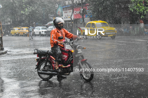 A food delivery person is waiting at a traffic signal during the heavy rain in Kolkata, India, on July 14, 2024. 