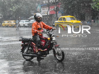 A food delivery person is waiting at a traffic signal during the heavy rain in Kolkata, India, on July 14, 2024. (