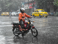 A food delivery person is waiting at a traffic signal during the heavy rain in Kolkata, India, on July 14, 2024. (