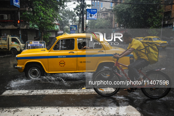 A woman is feeling the rain from a taxi during the heavy rain in Kolkata, India, on July 14, 2024. 