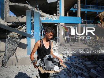 People are checking the destruction at a UN-run school after Israeli bombardment in Nuseirat, in the central Gaza Strip, on July 14, 2024, a...