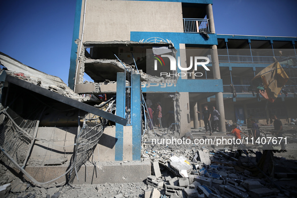 People are checking the destruction at a UN-run school after Israeli bombardment in Nuseirat, in the central Gaza Strip, on July 14, 2024, a...