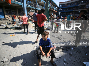 People are checking the destruction at a UN-run school after Israeli bombardment in Nuseirat, in the central Gaza Strip, on July 14, 2024, a...