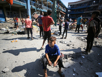 People are checking the destruction at a UN-run school after Israeli bombardment in Nuseirat, in the central Gaza Strip, on July 14, 2024, a...