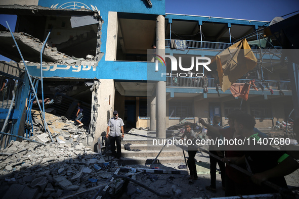 People are checking the destruction at a UN-run school after Israeli bombardment in Nuseirat, in the central Gaza Strip, on July 14, 2024, a...