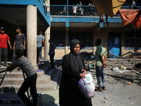 People are checking the destruction at a UN-run school after Israeli bombardment in Nuseirat, in the central Gaza Strip, on July 14, 2024, a...