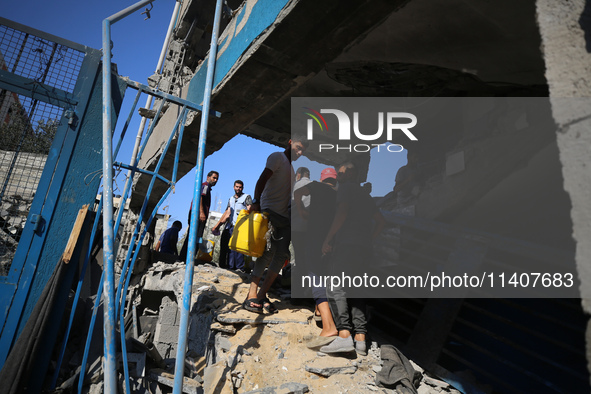 People are checking the destruction at a UN-run school after Israeli bombardment in Nuseirat, in the central Gaza Strip, on July 14, 2024, a...