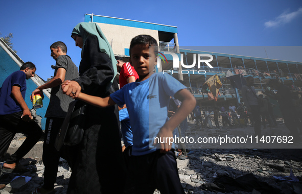 People are checking the destruction at a UN-run school after Israeli bombardment in Nuseirat, in the central Gaza Strip, on July 14, 2024, a...