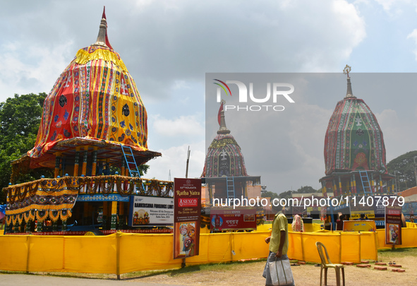 A person is passing next to chariots of Hindu lord Jagannath, Balaram, and Subhadra ahead of the Ulta Rath festival in Kolkata, India, on Ju...