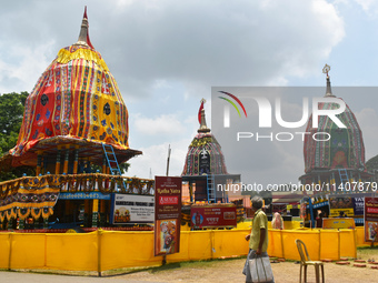 A person is passing next to chariots of Hindu lord Jagannath, Balaram, and Subhadra ahead of the Ulta Rath festival in Kolkata, India, on Ju...