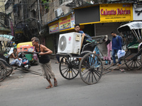 People are carrying an air conditioner into a hand-pulled rickshaw on a hot day in Kolkata, India, on July 14, 2024. (