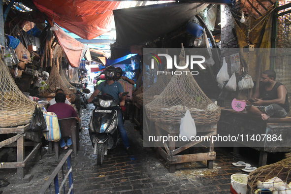 People are riding on a scooter inside a market in Kolkata, India, on July 14, 2024. 