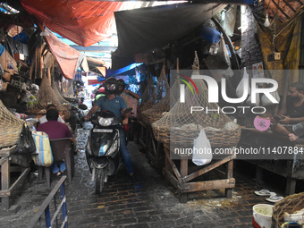 People are riding on a scooter inside a market in Kolkata, India, on July 14, 2024. (