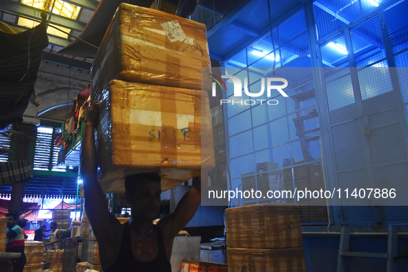 A person is carrying products on his head inside a market in Kolkata, India, on July 14, 2024. 