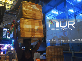 A person is carrying products on his head inside a market in Kolkata, India, on July 14, 2024. (