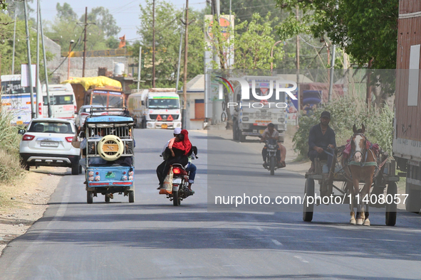 People are traveling by horse cart along a road in Najibabad, Uttar Pradesh, India, on April 19, 2024. 