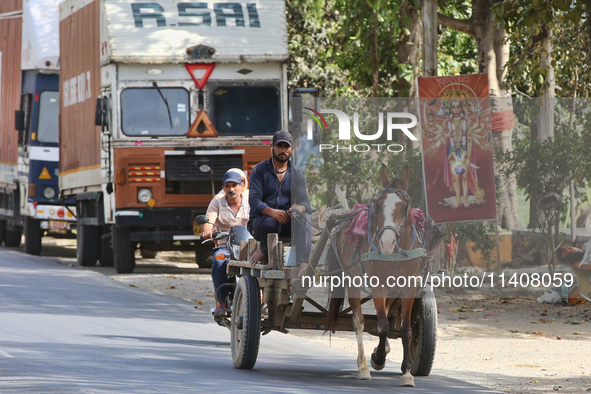 People are traveling by horse cart along a road in Najibabad, Uttar Pradesh, India, on April 19, 2024. 