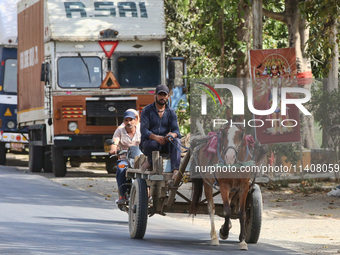 People are traveling by horse cart along a road in Najibabad, Uttar Pradesh, India, on April 19, 2024. (