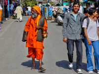 A sadhu is walking past a young couple along Mall Road in Mussoorie, Uttarakhand, India, on April 18, 2024. (