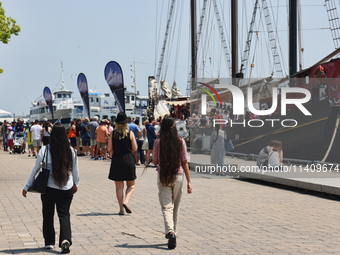 People are walking along the boardwalk at Harbourfront in Toronto, Ontario, Canada, on July 13, 2024. (