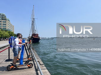 People are riding scooters along the boardwalk at Harbourfront in Toronto, Ontario, Canada, on July 13, 2024. (