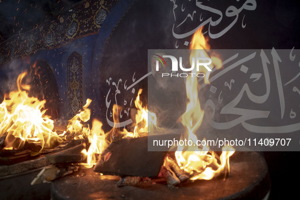 An Iraqi man living in Iran is preparing fire for baking donated meals for worshippers during a religious rally to commemorate Tasoua, in Do...