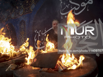 An Iraqi man living in Iran is preparing fire for baking donated meals for worshippers during a religious rally to commemorate Tasoua, in Do...