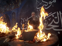 An Iraqi man living in Iran is preparing fire for baking donated meals for worshippers during a religious rally to commemorate Tasoua, in Do...