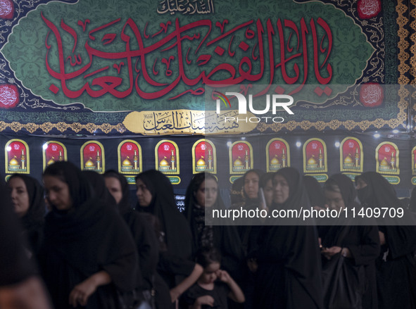 Veiled women are standing in line while waiting to receive donated meals and participating in a religious rally to commemorate Tasoua, in Do...