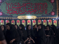 Veiled women are standing in line while waiting to receive donated meals and participating in a religious rally to commemorate Tasoua, in Do...