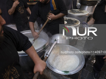 Iraqi men living in Iran are preparing donated meals for worshippers during a religious rally to commemorate Tasoua, in Dolatabad neighborho...