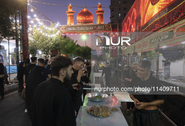 A worshipper is drinking donated tea during a religious rally to commemorate Tasoua in the Dolatabad neighborhood in southern Tehran, Iran,...