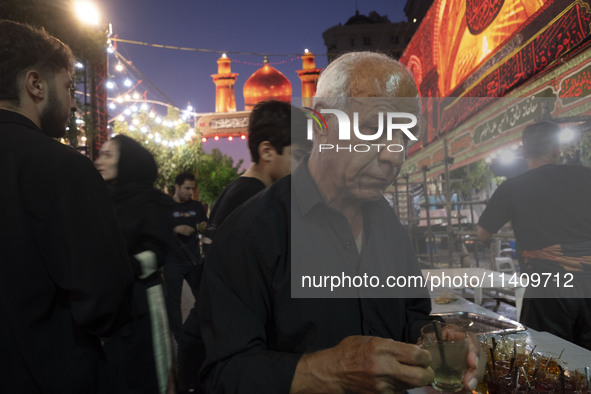 A worshipper is receiving donated tea during a religious rally to commemorate Tasoua in the Dolatabad neighborhood in southern Tehran, Iran,...