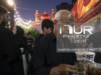 A worshipper is receiving donated tea during a religious rally to commemorate Tasoua in the Dolatabad neighborhood in southern Tehran, Iran,...