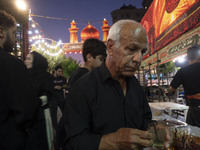 A worshipper is receiving donated tea during a religious rally to commemorate Tasoua in the Dolatabad neighborhood in southern Tehran, Iran,...