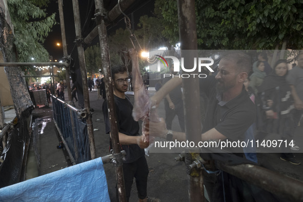 An Iraqi man living in Iran is preparing meat for baking donated meals for worshippers during a religious rally to commemorate Tasoua, in Do...