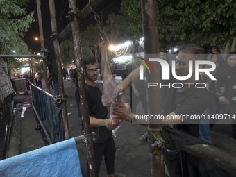 An Iraqi man living in Iran is preparing meat for baking donated meals for worshippers during a religious rally to commemorate Tasoua, in Do...