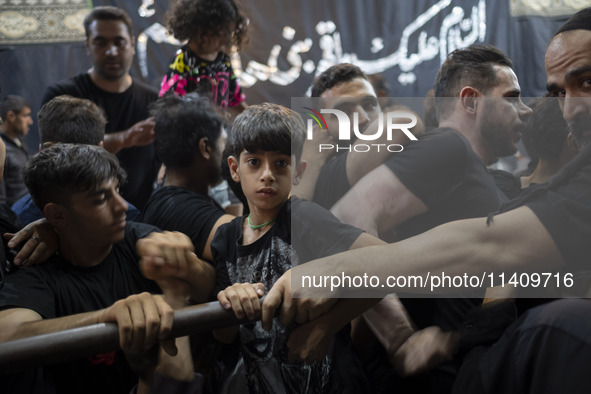 A young boy is looking on while waiting to receive donated meals during a religious rally to commemorate Tasoua, in Dolatabad neighborhood i...