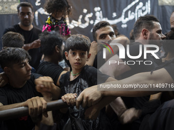 A young boy is looking on while waiting to receive donated meals during a religious rally to commemorate Tasoua, in Dolatabad neighborhood i...