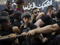 A young boy is looking on while waiting to receive donated meals during a religious rally to commemorate Tasoua, in Dolatabad neighborhood i...