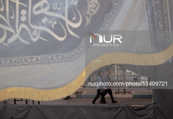 A couple is walking under a religious flag while participating in a religious rally to commemorate Tasoua, in Dolatabad neighborhood in sout...