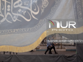 A couple is walking under a religious flag while participating in a religious rally to commemorate Tasoua, in Dolatabad neighborhood in sout...