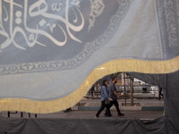 A couple is walking under a religious flag while participating in a religious rally to commemorate Tasoua, in Dolatabad neighborhood in sout...