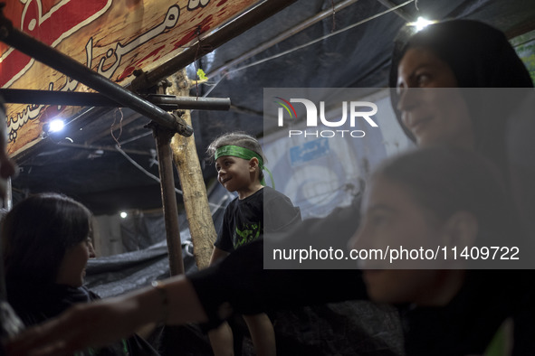 A young boy is wearing a religious headband while participating with his family in a religious rally to commemorate Tasoua, in Dolatabad nei...