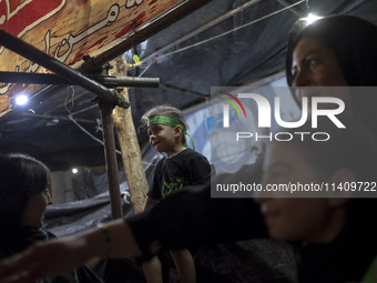 A young boy is wearing a religious headband while participating with his family in a religious rally to commemorate Tasoua, in Dolatabad nei...